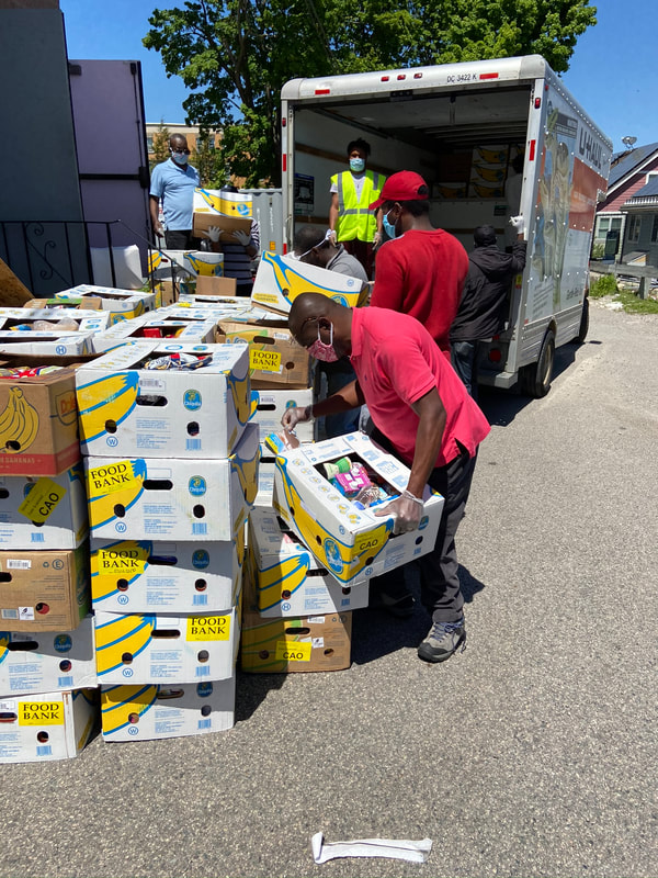 Volunteers and staff unload food from a truck outside a food bank.